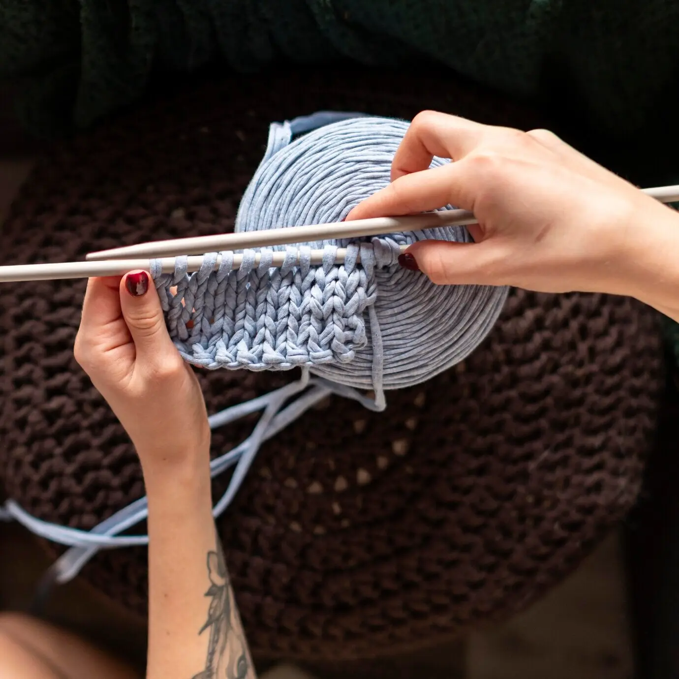 Nahaufnahme einer Frau beim Häkeln aus der Draufsicht.